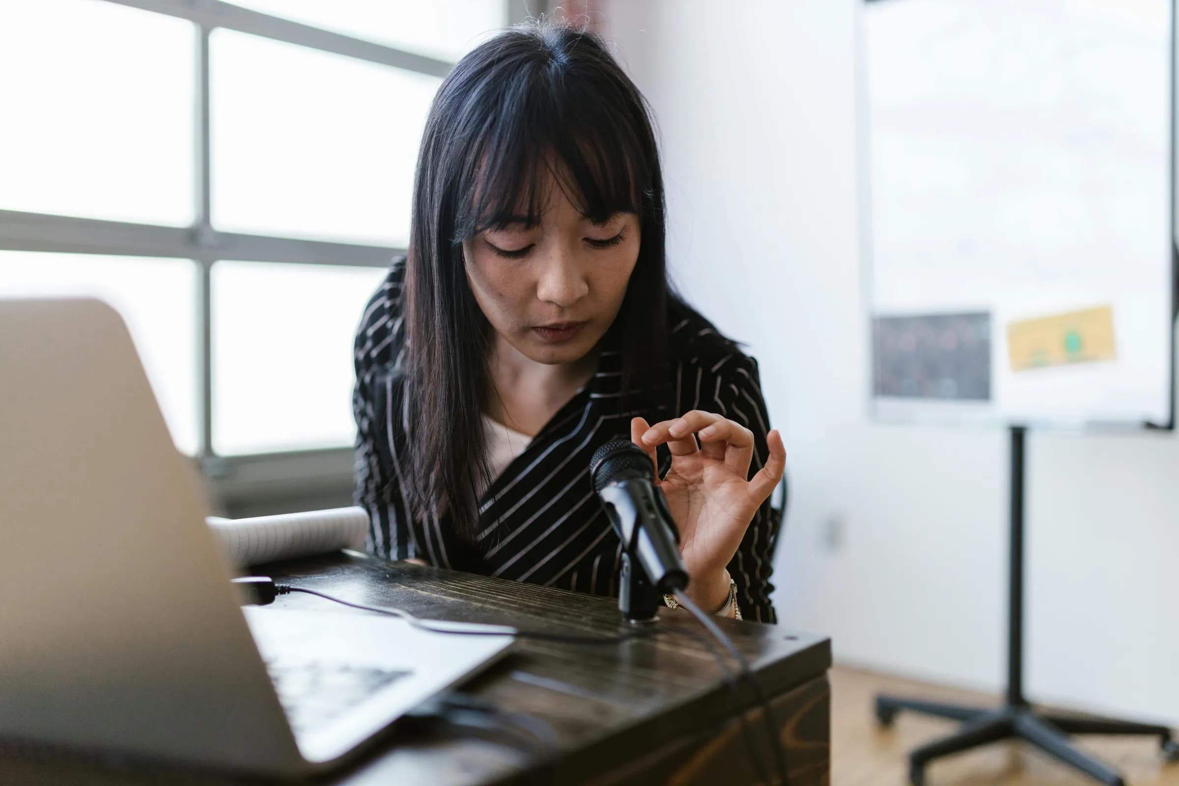 Person at a desk talking into a microphone next to an open laptop, illustrating talk-to-text dictation