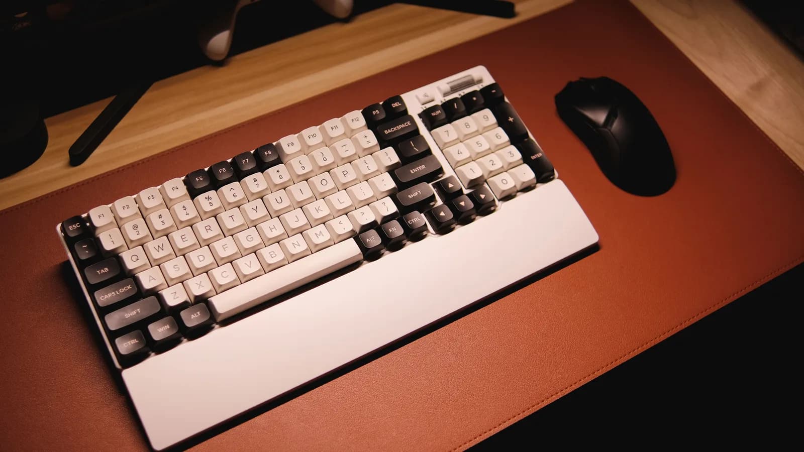 Et mekanisk tastatur og mus på en læder-skrivebordsunderlag, varmt oplyst — det stemmeindtastning lader dig røre mindre