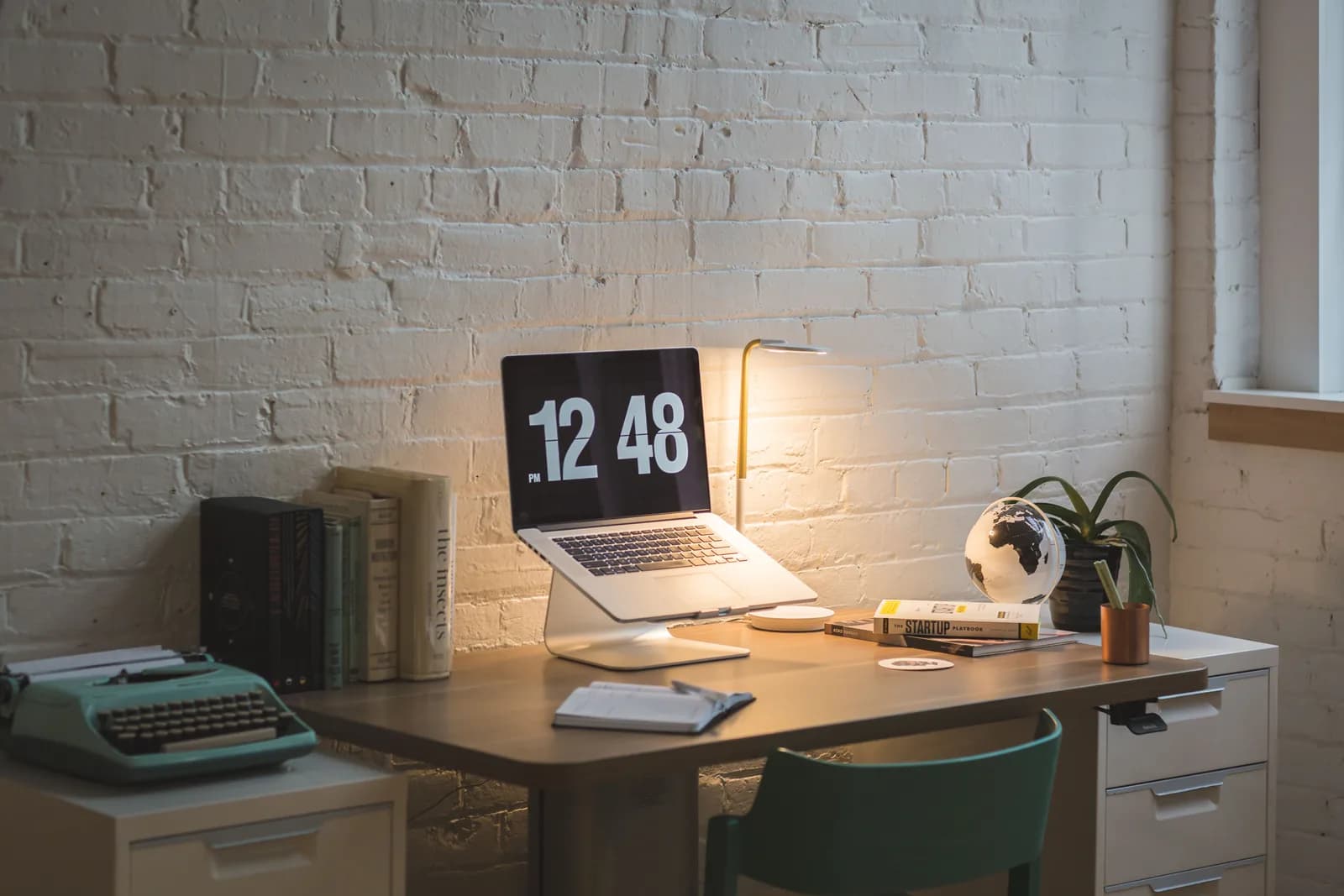 Organized desk with a laptop, books and a lamp set up for focused design work