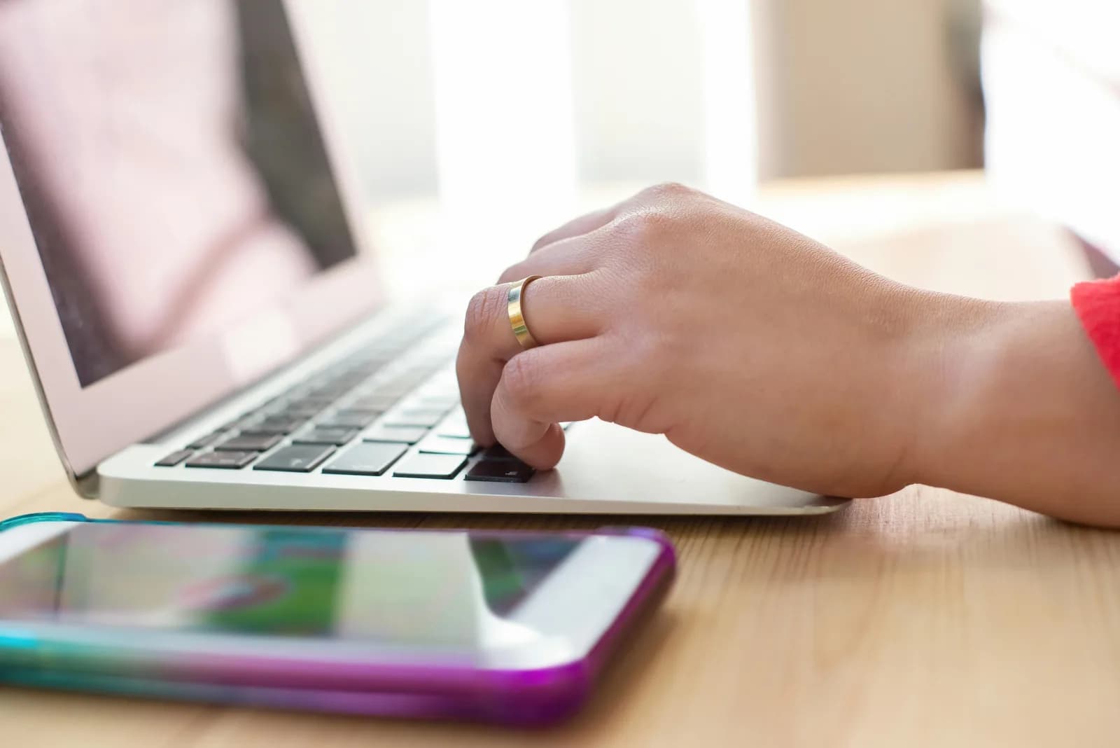A keyboard on a desk with a person's hands resting nearby, not typing