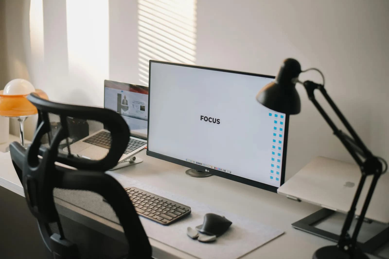 Clean modern home-office desk with a monitor and ambient light, illustrating focused workday tradeoffs