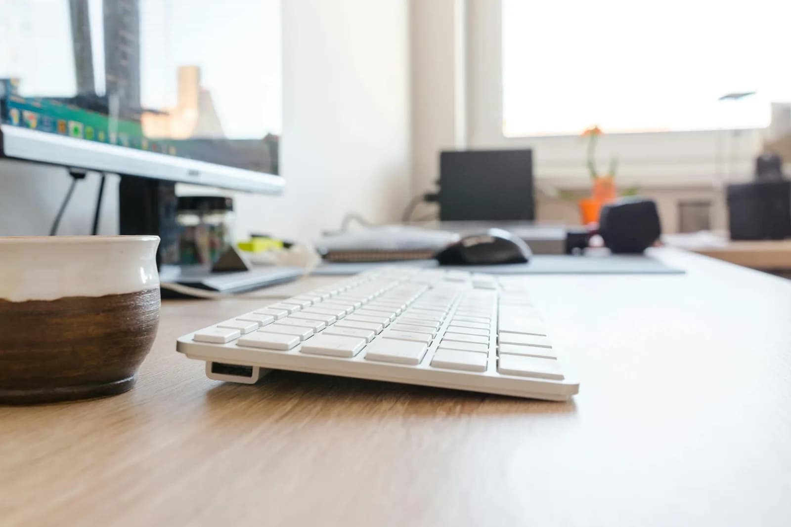 A clean desk with a wireless keyboard and a coffee cup, the kind of setup you'd build a spreadsheet at