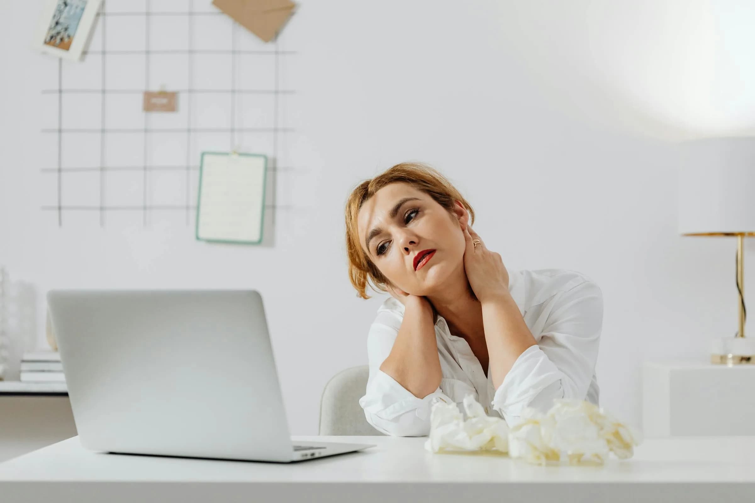 Vermoeid persoon aan een opgeruimd bureau die naar een zilveren laptop staart, het moment waarop Mac Dictation gewoon stopt met werken