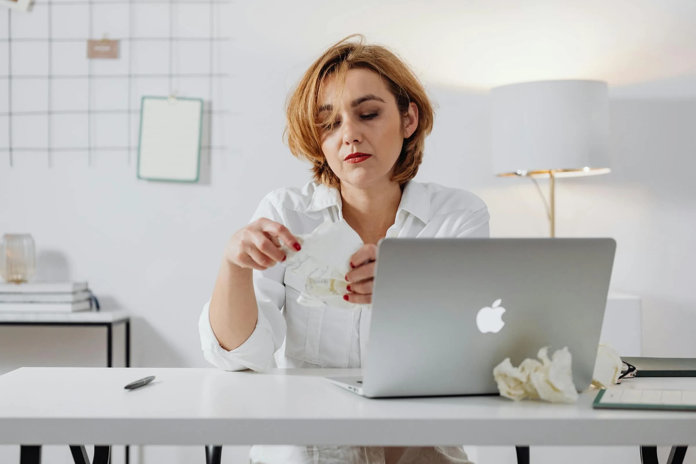 Persoon aan een laptop omringd door verfrommeld papier, de cyclus van het herhaaldelijk fixen van dezelfde dictation-bug