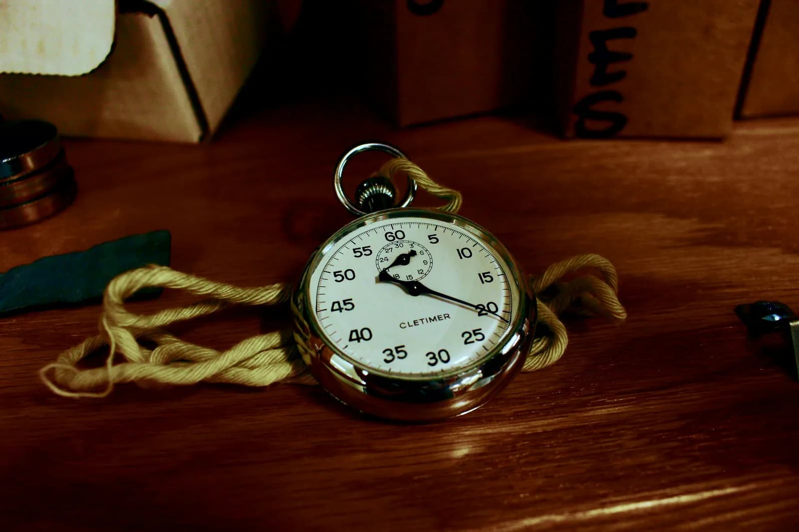 Silver stopwatch resting on a wooden table, evoking a silence timer that ends dictation