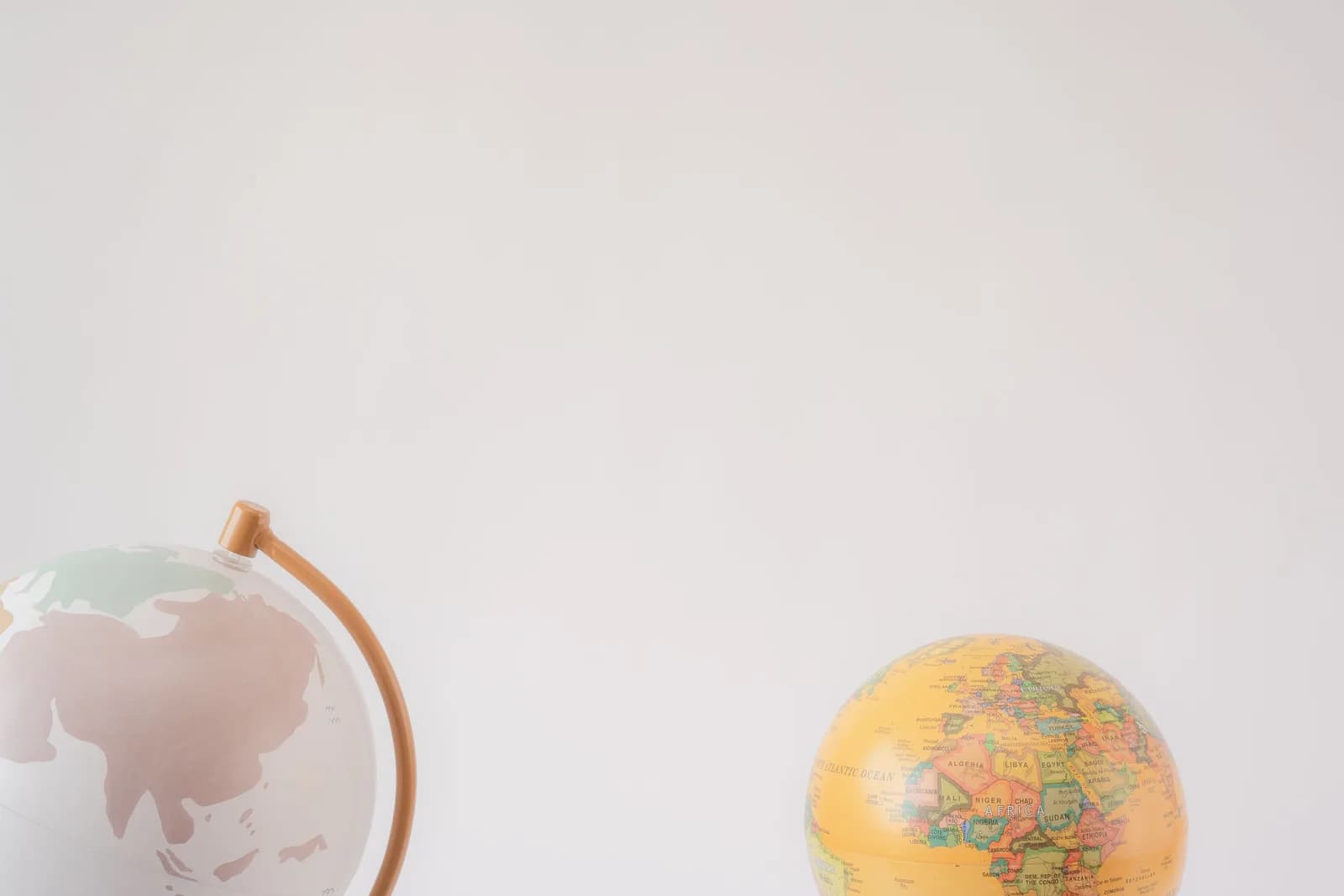 Two world globes on a gray background, standing in for choosing the right language and accent